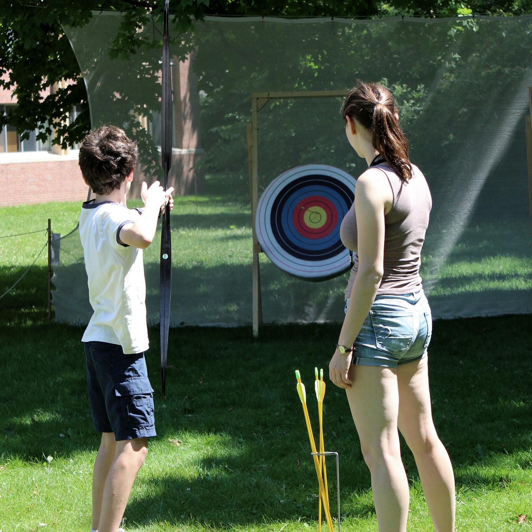 Green Cove counselor instructing archery to a camper.